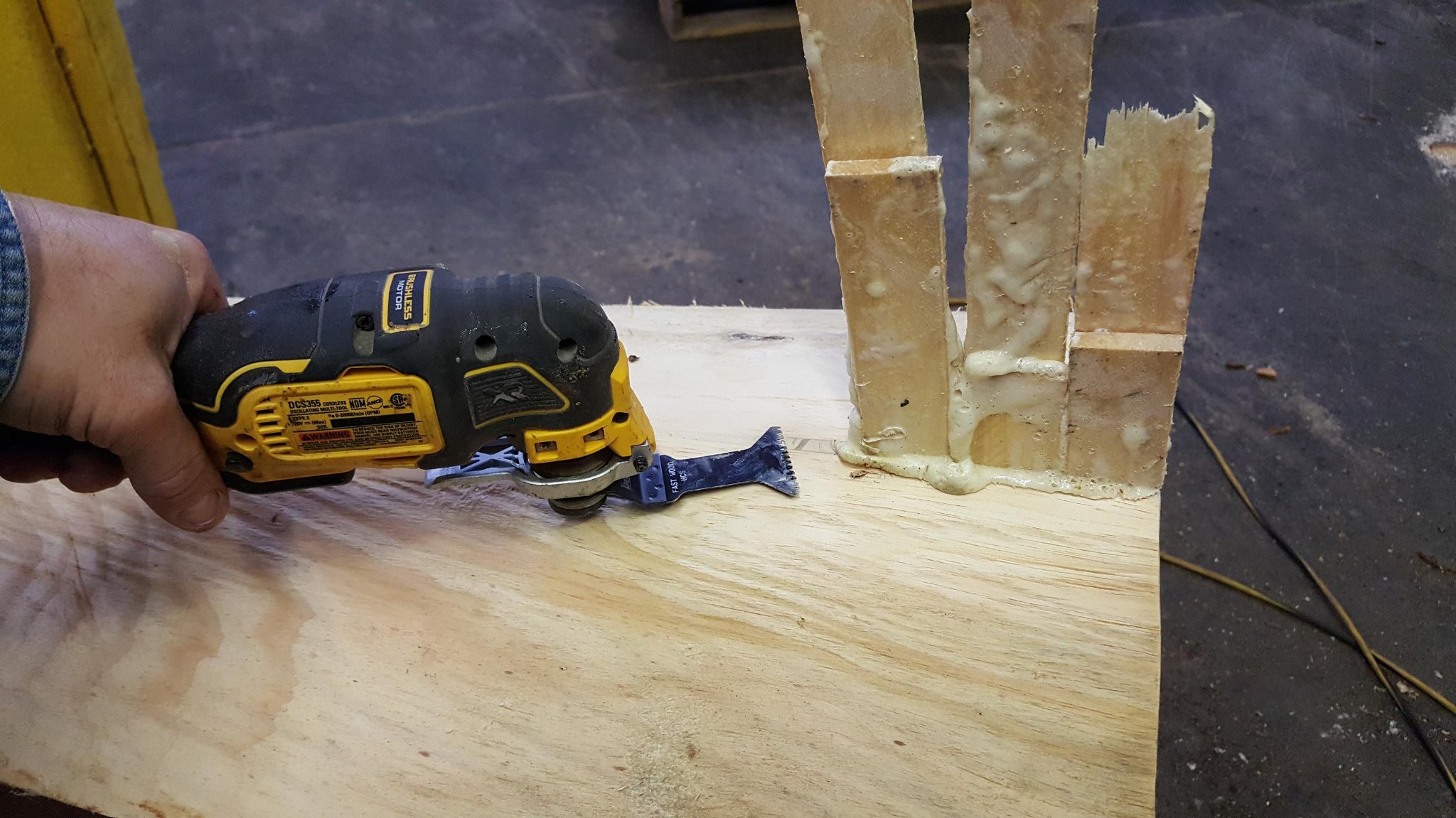 DeWalt oscillating multi-tool trimming excess cured foam flush with the surface of the hollow log